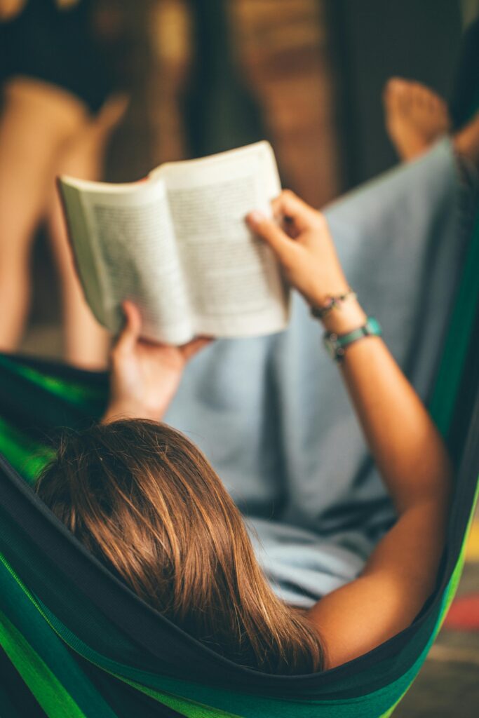 A woman enjoying a peaceful moment reading in a hammock on a sunny day.