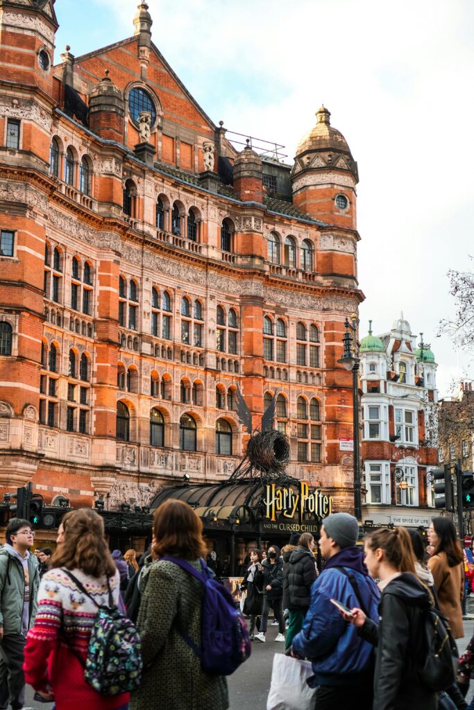 Crowd outside a historic theater in London with Harry Potter signage amid stunning architecture.