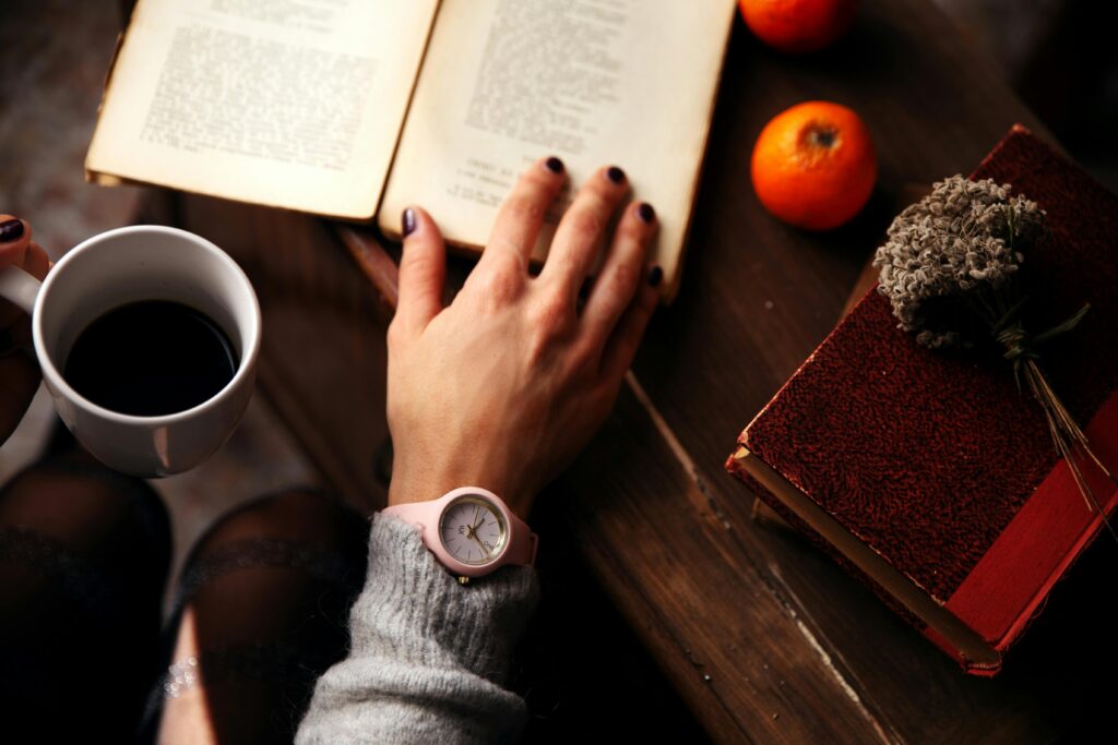 Cozy scene of a person enjoying a book with coffee and oranges, highlighting relaxation.