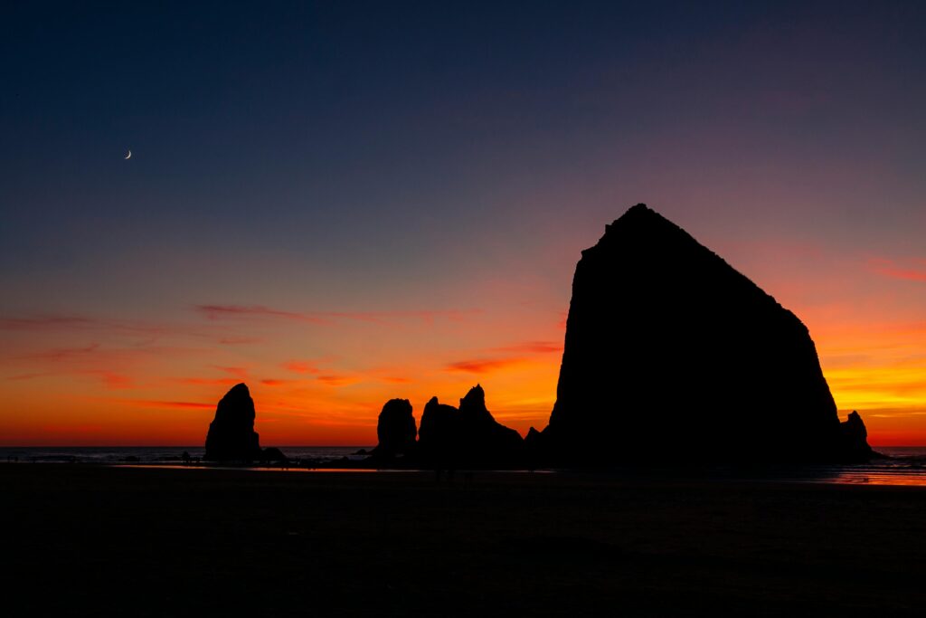 Stunning view of Haystack Rock silhouetted against a vibrant sunset at Cannon Beach.