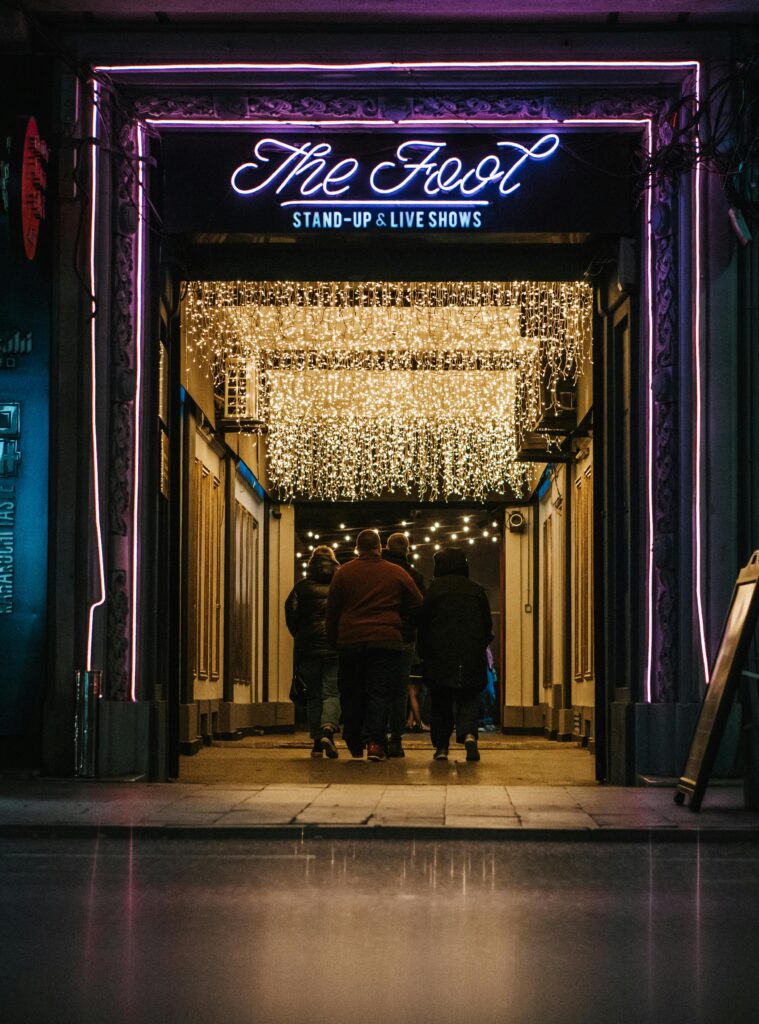 Group of people entering a neon-lit theater in Bucharest, Romania, for stand-up shows.