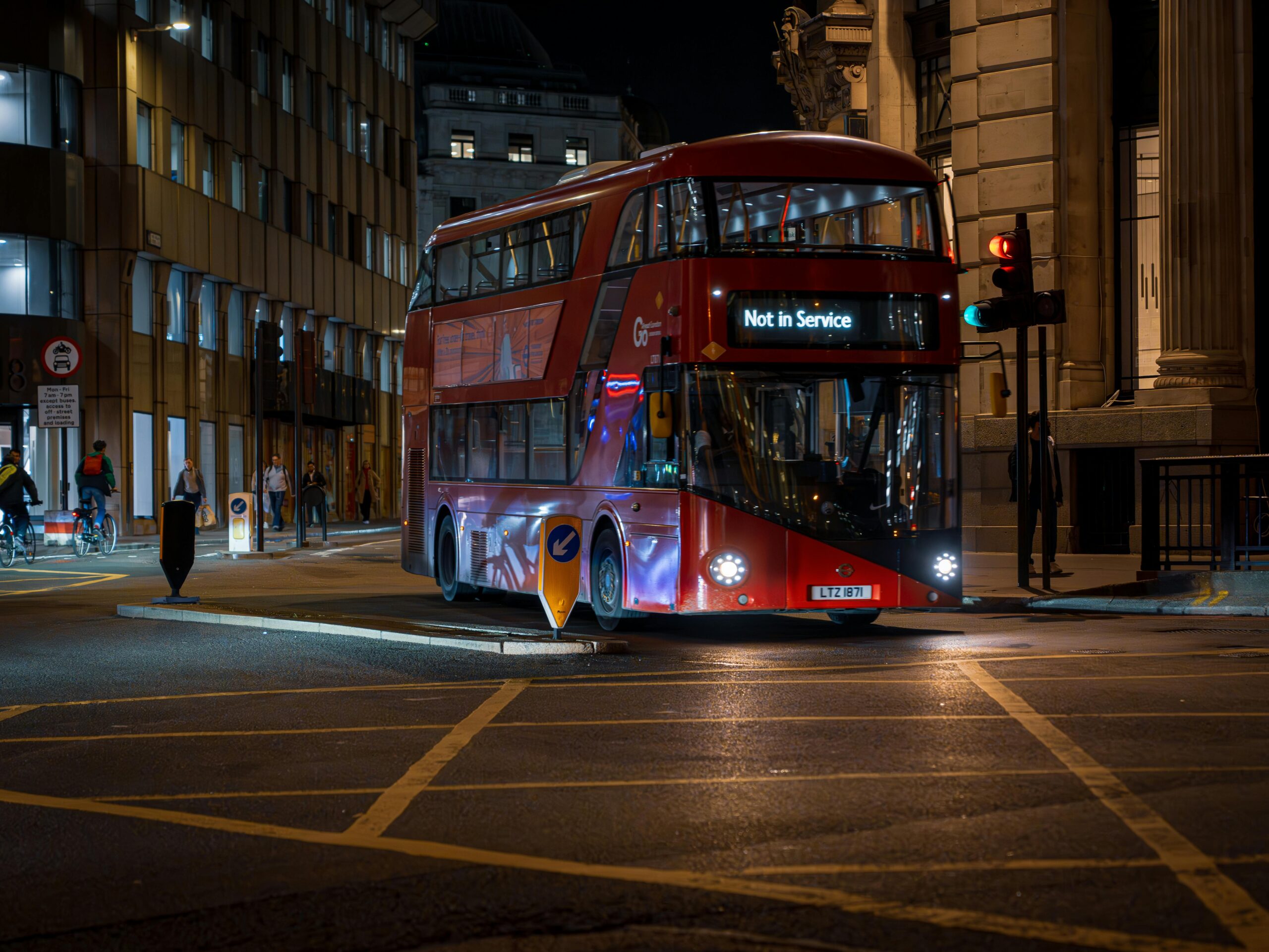 Red double-decker bus not in service on London's city streets at night.