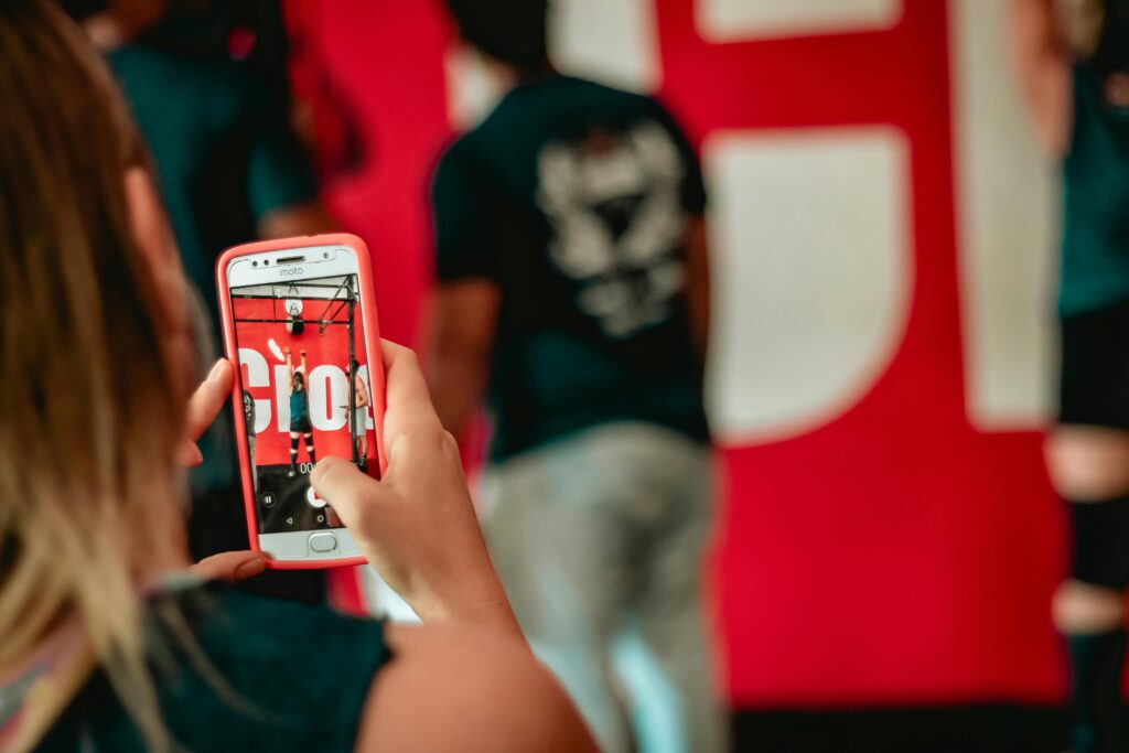 A woman captures a moment at an event on her smartphone indoors.
