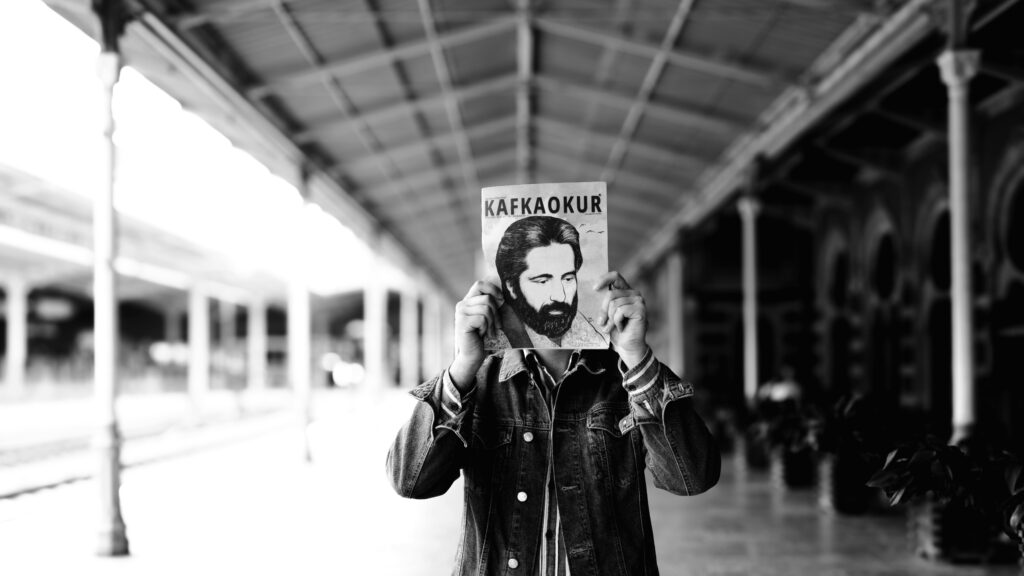Artistic black and white portrait at Istanbul train station with a Kafka magazine.