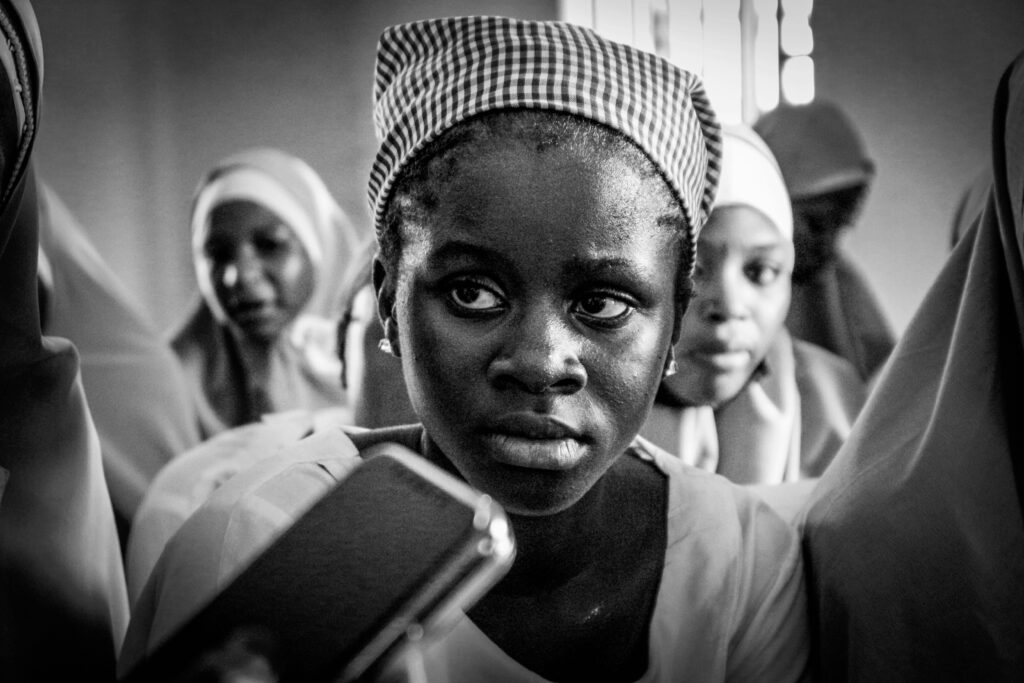 Black and white portrait of Nigerian girls wearing traditional headscarves in a cultural setting.