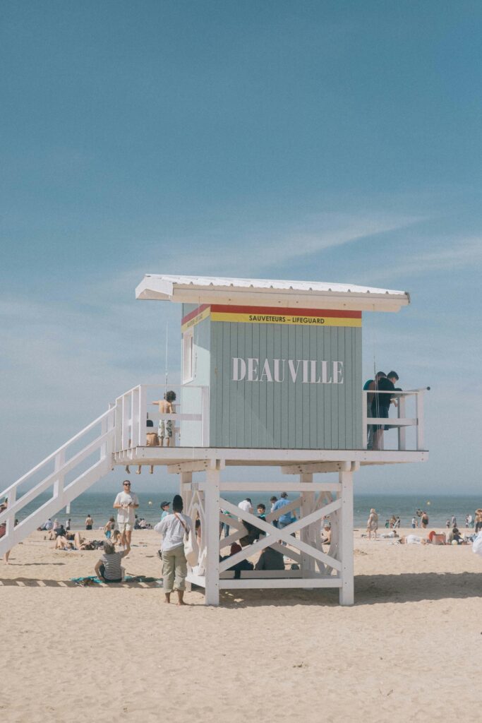 A busy summer day at Deauville Beach with sunbathers near a lifeguard tower.