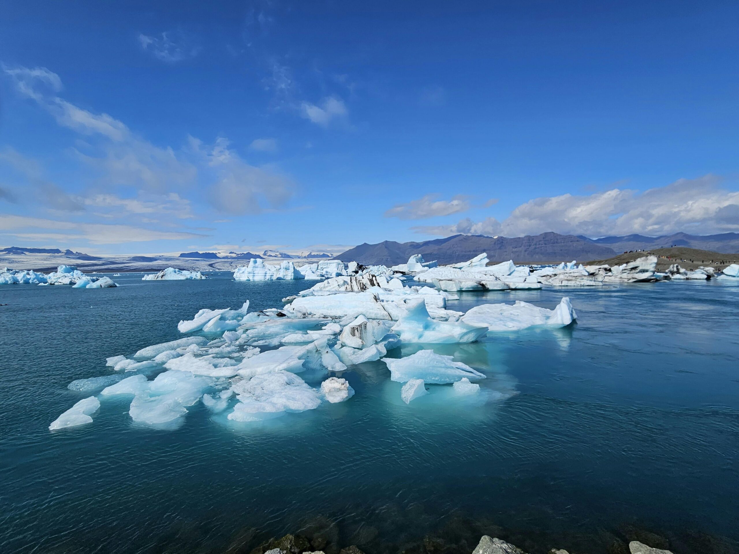Captivating view of icebergs floating in Jökulsárlón, Iceland, under a clear blue sky.