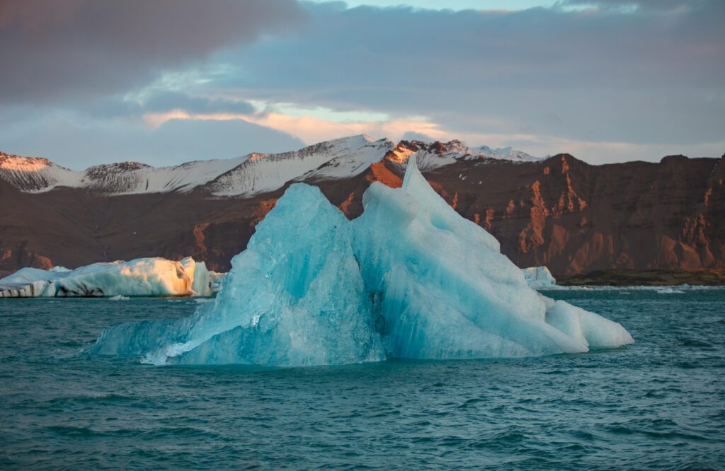 Majestic iceberg floating in serene Icelandic waters under a vibrant sunset. Perfect nature and travel image.