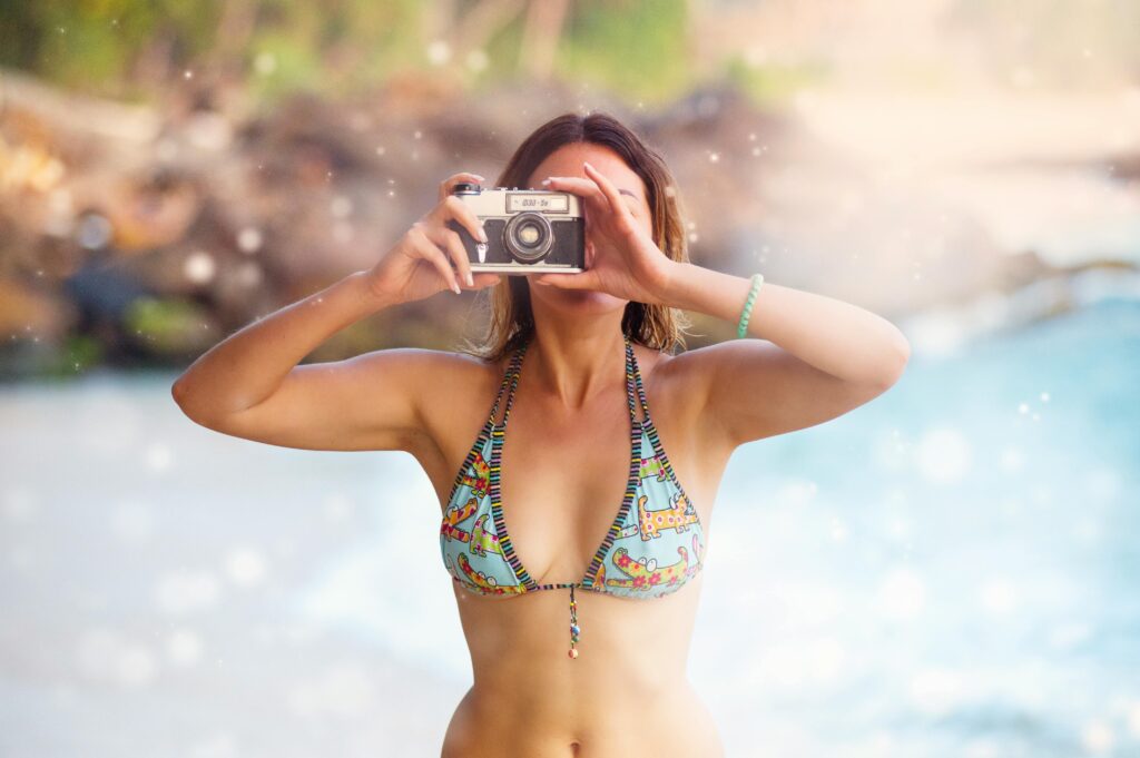 Woman in a bikini captures beach memories in Unawatuna, Sri Lanka with a vintage camera.