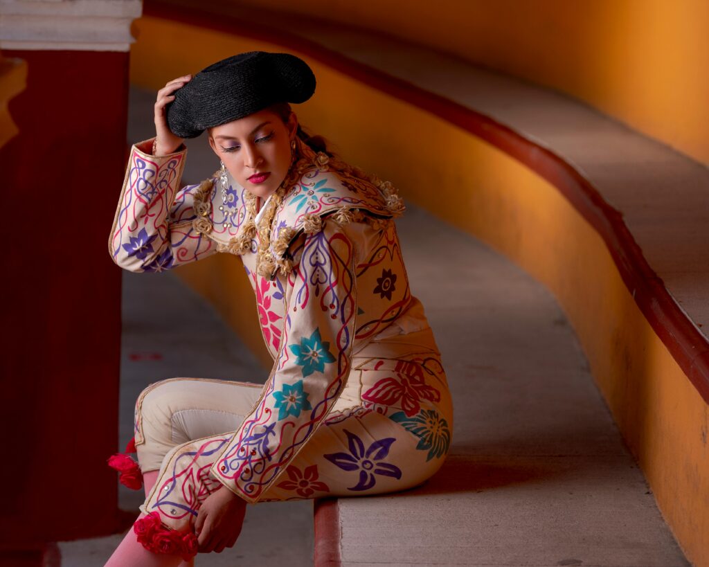 A vibrant portrait of a person in traditional matador attire with intricate embroidery, seated in a colorful setting.