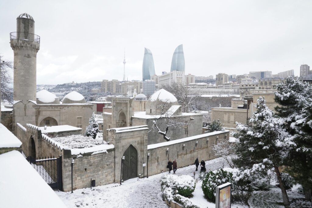 A winter view of Baku's historic Old City with prominent Flame Towers in the background.