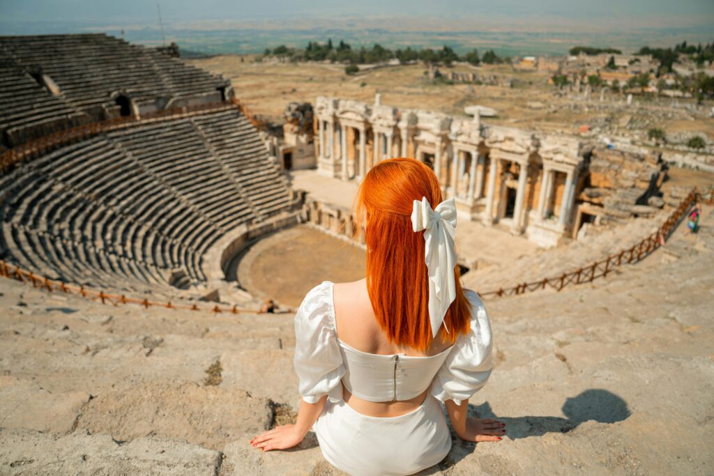A woman with red hair sits at the ancient Hierapolis theatre in Denizli, Turkey.