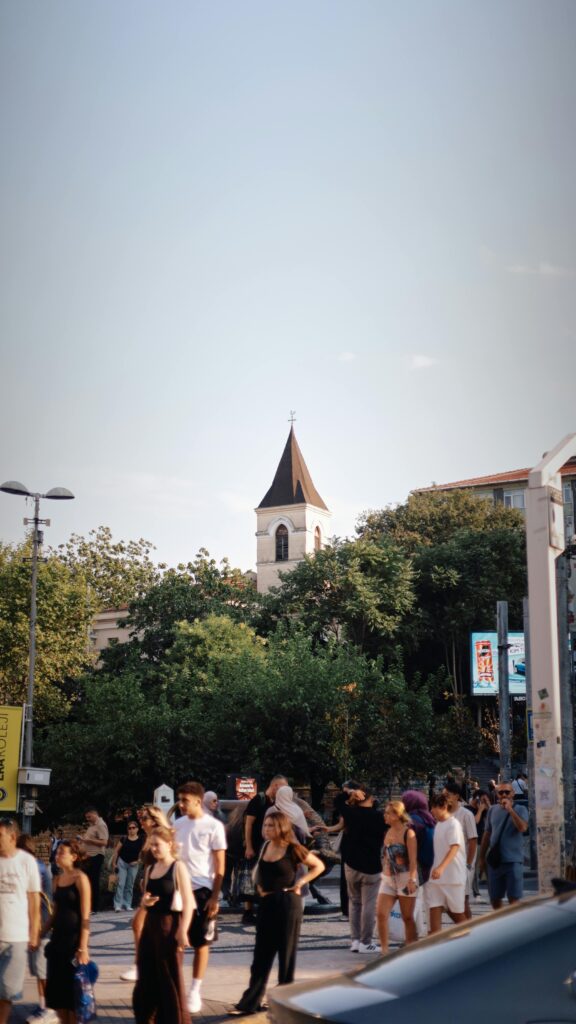 A bustling street scene in Istanbul with a historic church tower in the background.