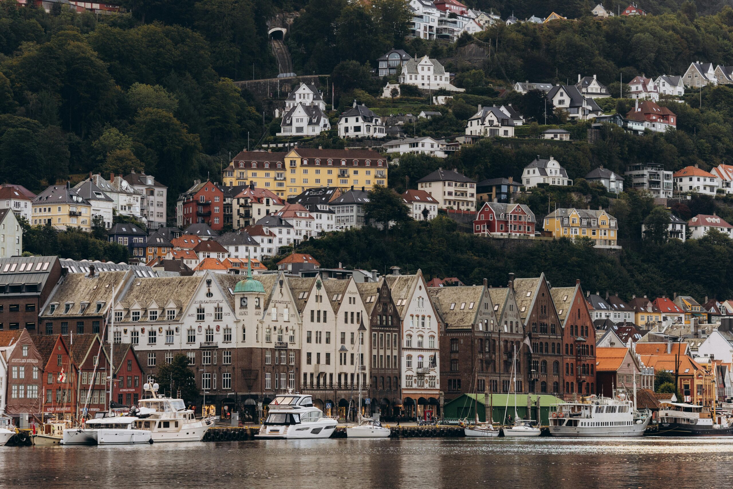 Scenic view of Bryggen and hillside houses in Bergen, Norway on a cloudy day.