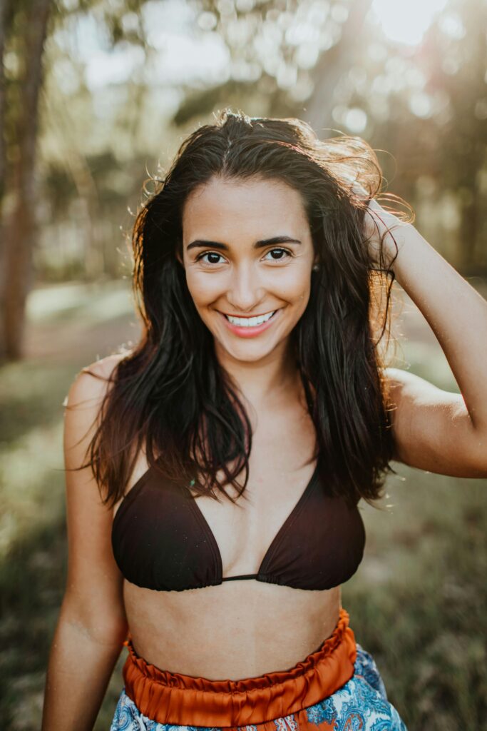 Carefree woman in bikini enjoying sunny day outdoors with a vibrant smile.