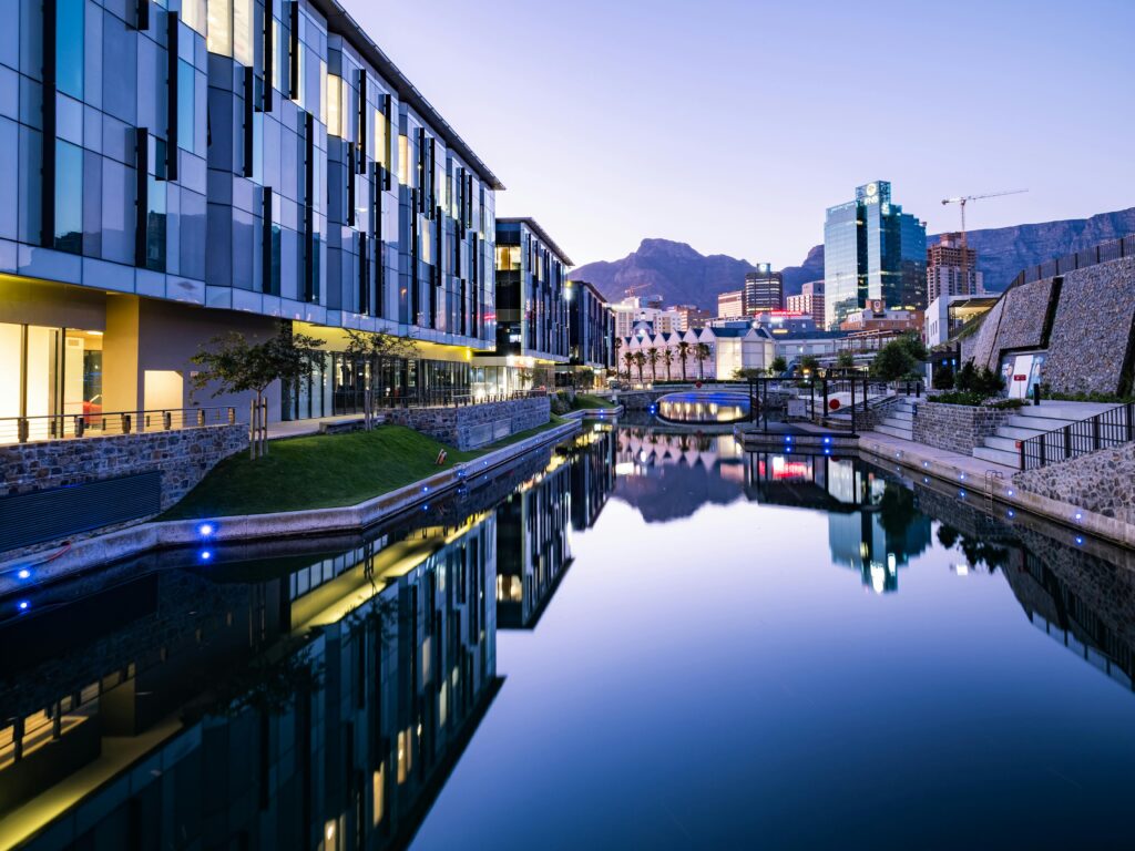 Stunning view of modern buildings reflecting on a canal in Cape Town at twilight.