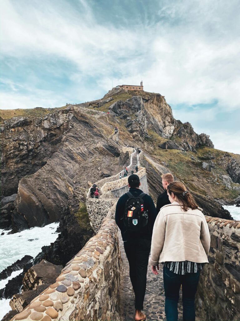 Tourists walking up the scenic stairs of Gaztelugatxe, an iconic island off the coast of Spain.