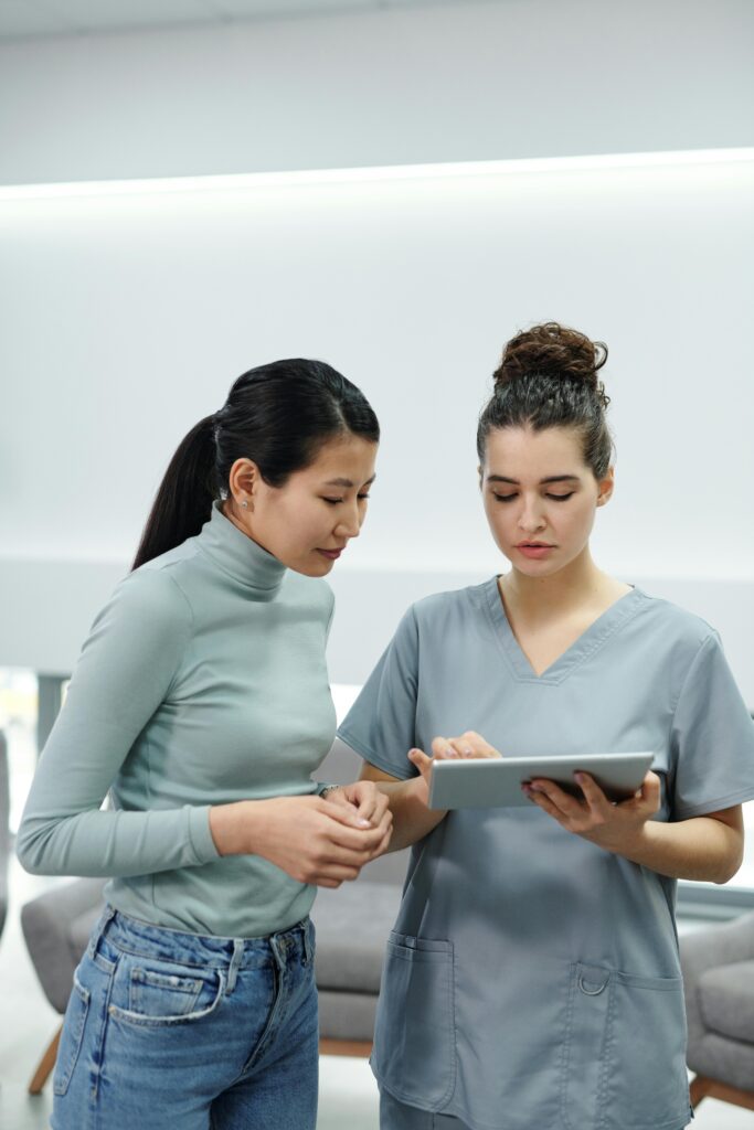 Healthcare professional using a tablet during a consultation inside a clinic.