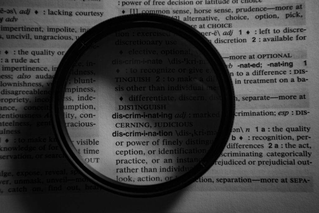 Dictionary page close-up with a magnifier highlighting the word 'discrimination.'