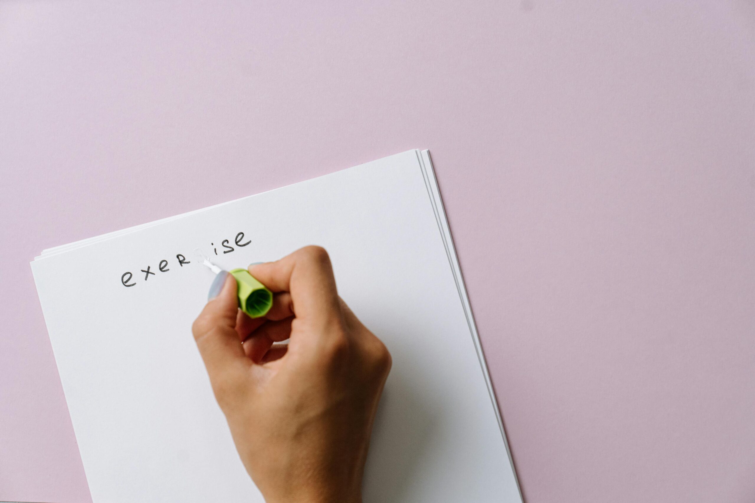 A hand using correction fluid to fix a spelling error on paper.