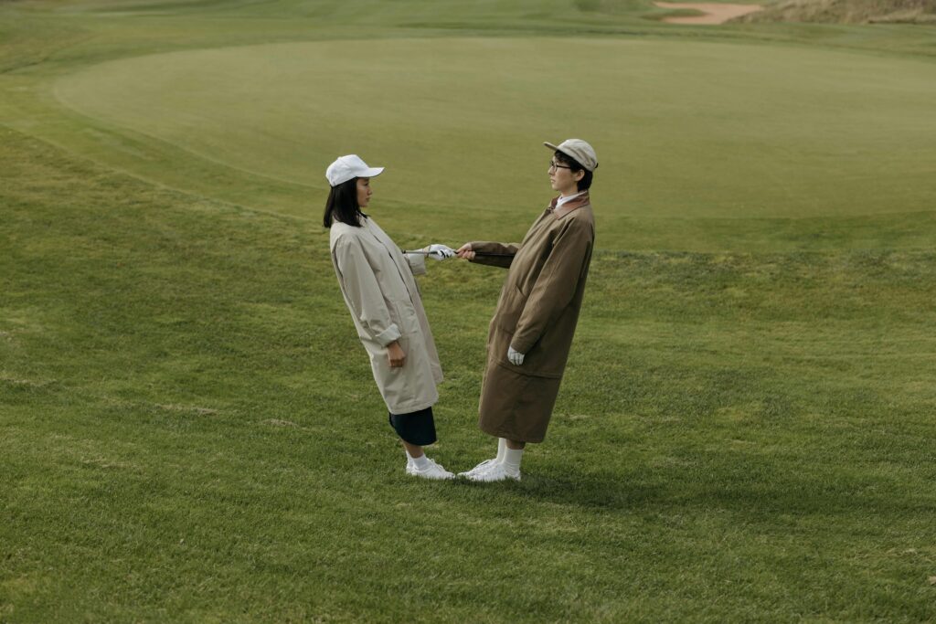 Two individuals playfully interacting on a lush golf course on a sunny day.