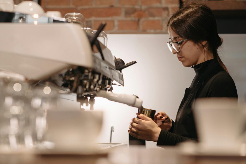 A focused barista expertly brews coffee using an espresso machine in a cozy cafe setting.