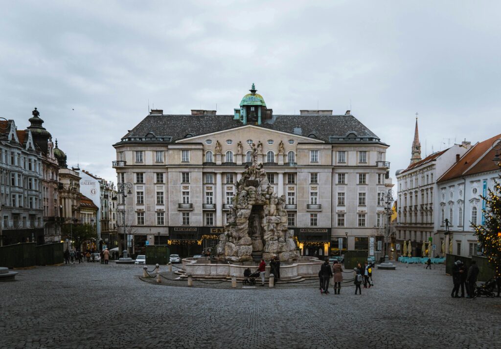 Explore the historic town square in Brno, Czechia, featuring classic architecture and a central fountain.