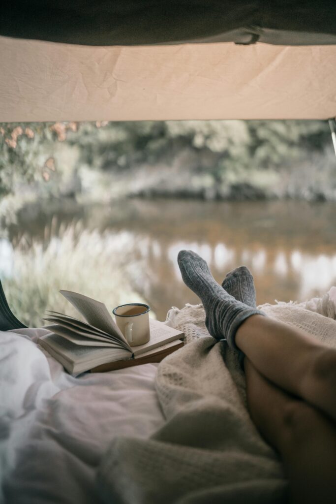 Relax in a tent with a book and coffee by a tranquil lake.