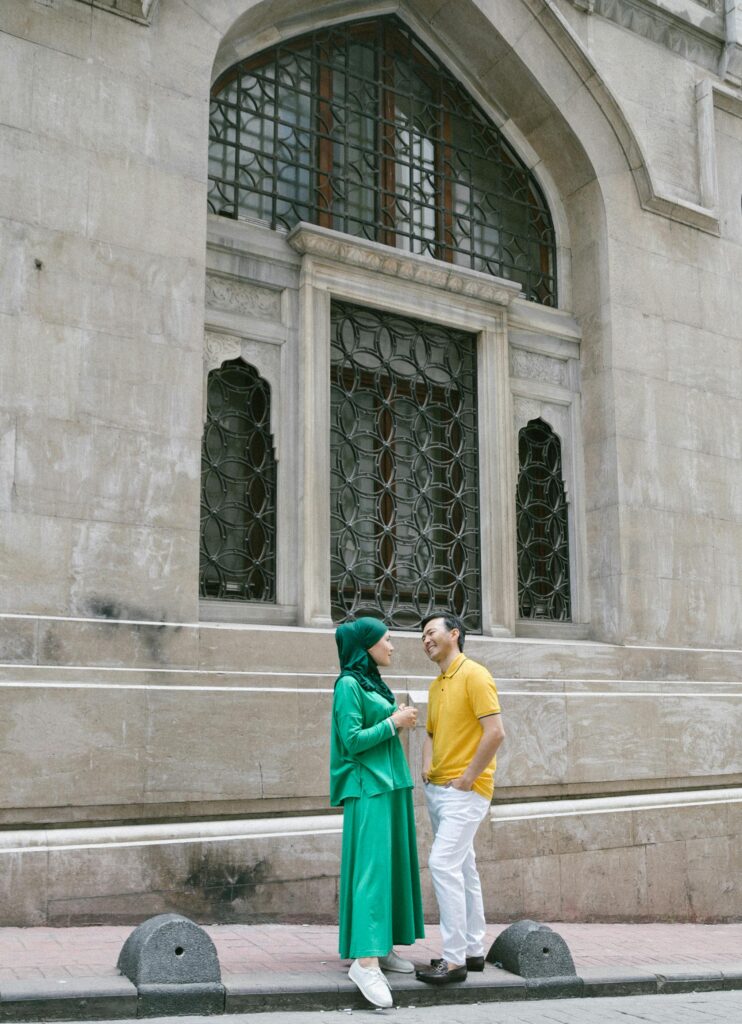 A joyful Muslim couple interacts outside a historic building in Istanbul, Turkey.