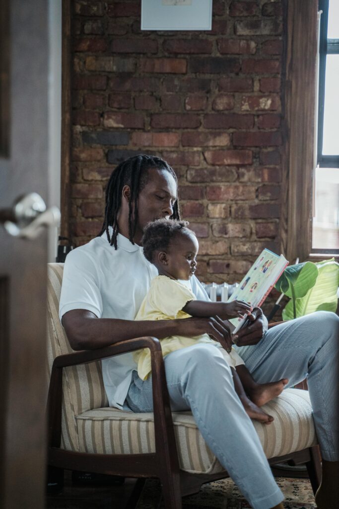 A father and child bonding while reading a book together at home, creating a warm family moment.