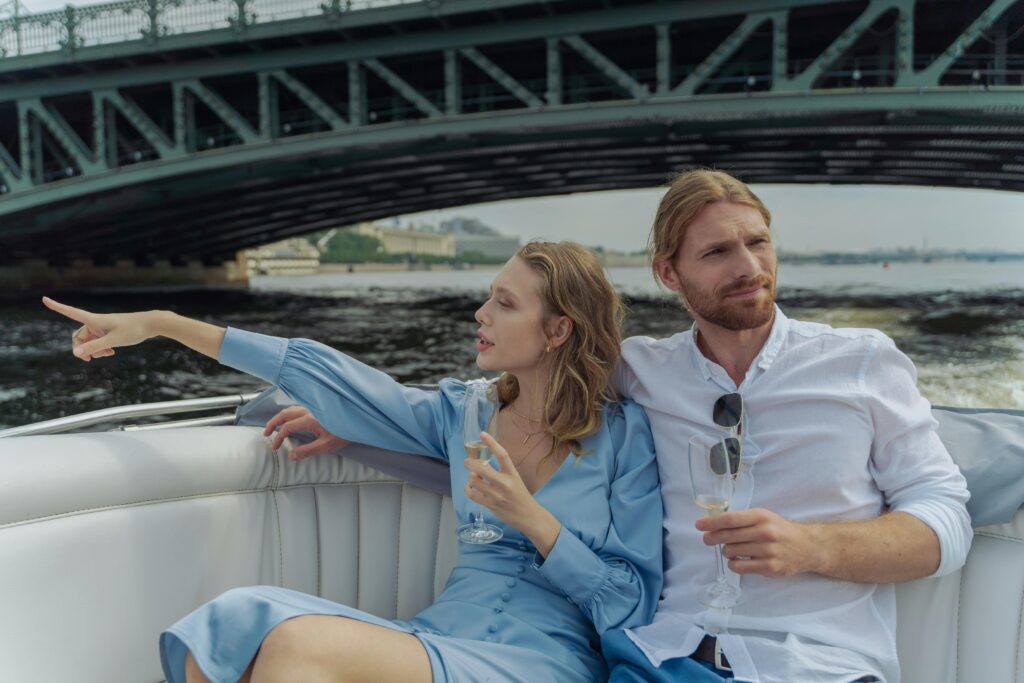 Couple enjoying a romantic boat ride under a bridge, sipping champagne.