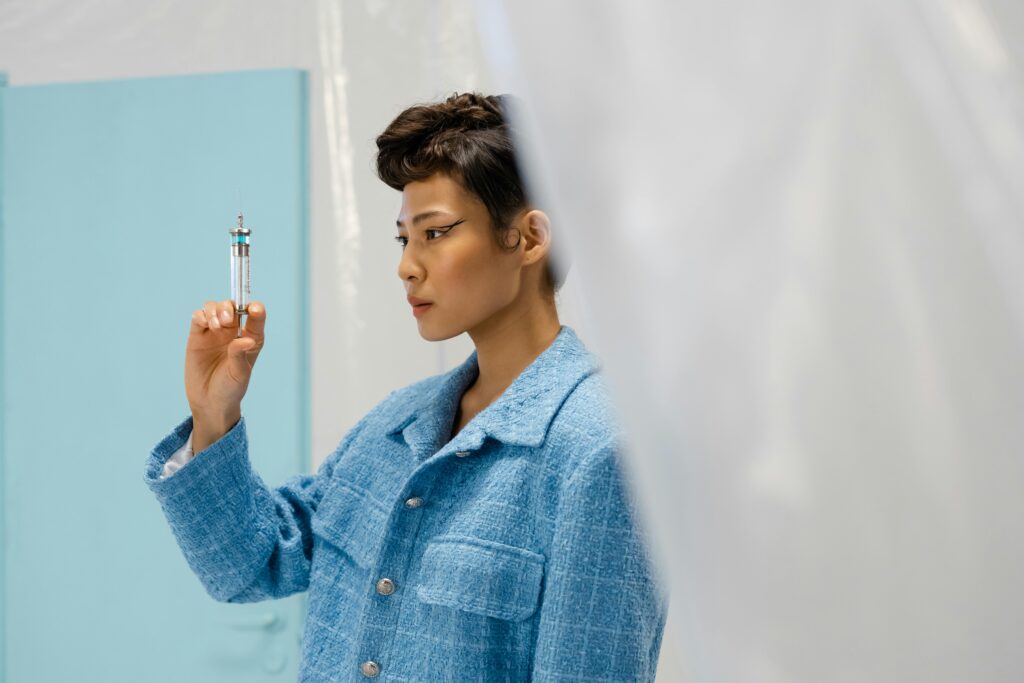 A woman in blue attire examines a syringe, highlighting modern medical research indoors.
