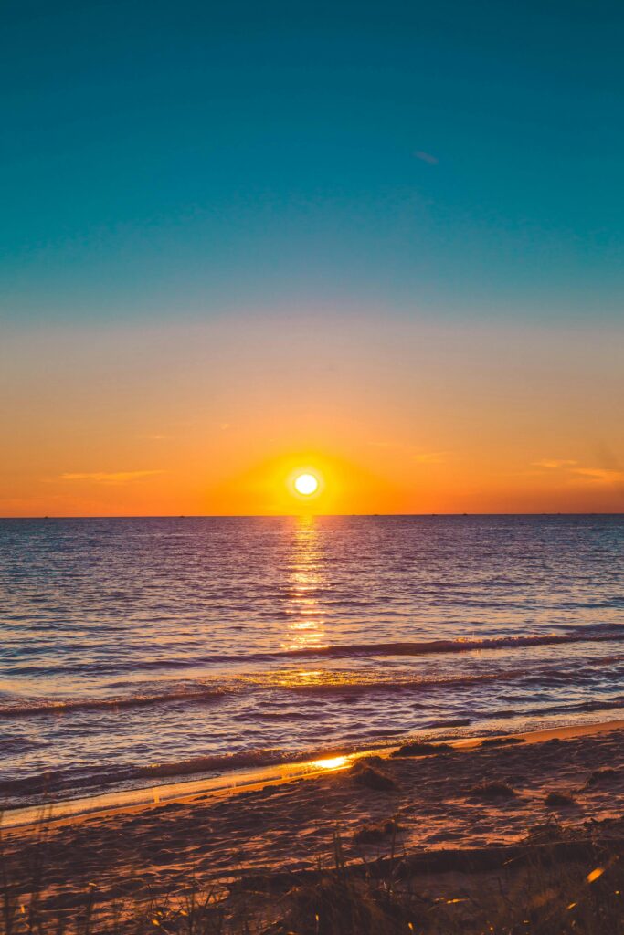 Beautiful sunset over a calm ocean with vibrant sky, perfect for relaxation themes.