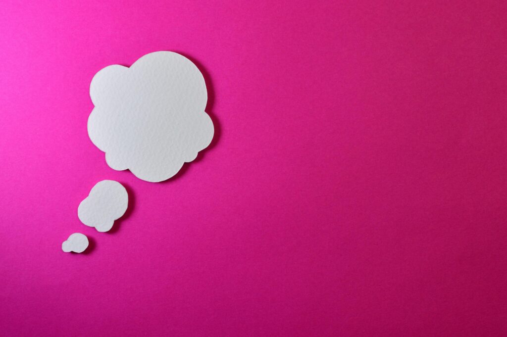 Paper thought bubble over bright pink background, ideal for creative concepts.