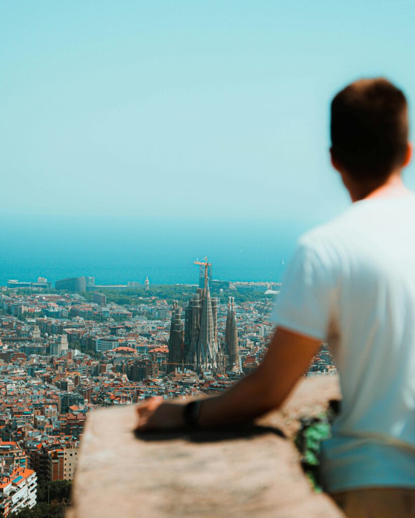 Man overlooking Barcelona's cityscape with La Sagrada Familia in view.