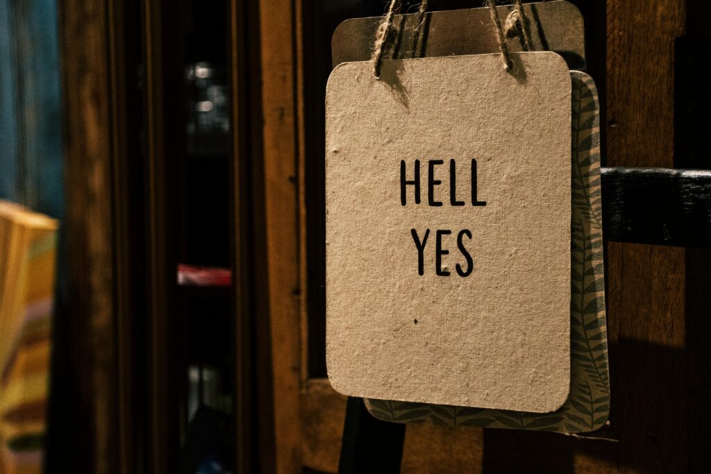 A vintage-style sign with the words 'HELL YES' hanging indoors, offering a motivational and rustic vibe.