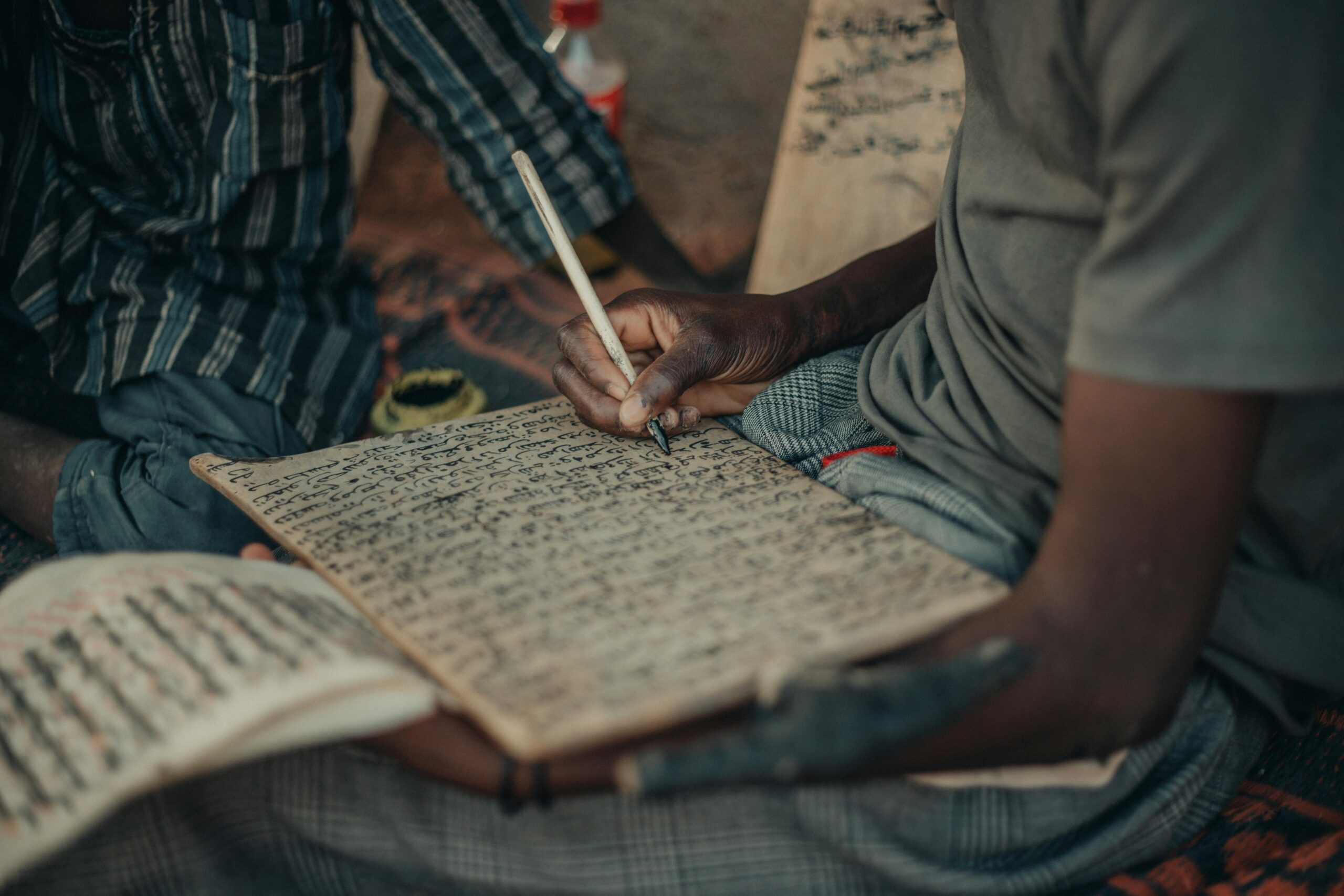 Close-up of a man writing with a wooden pen in Kano, Nigeria.