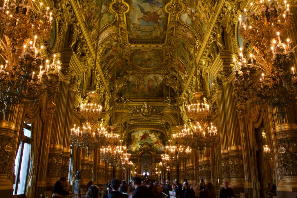 Majestic inside view of the opulent Palais Garnier with chandeliers and ornate ceiling.