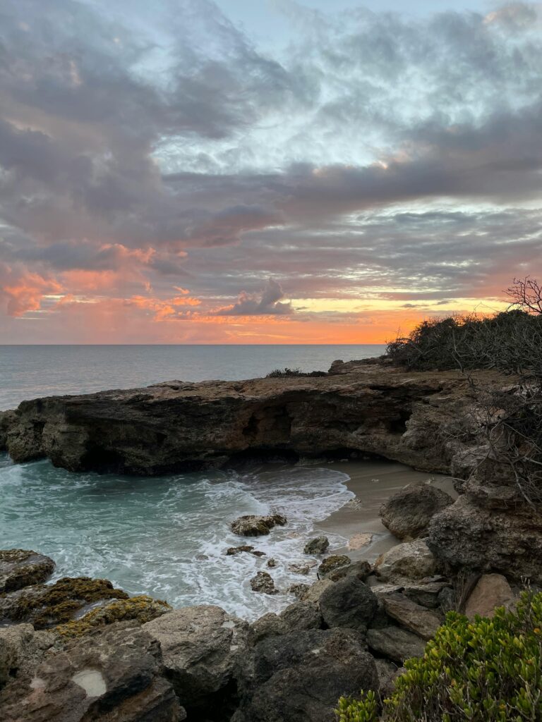 Beautiful rocky beach at sunset in St. Croix, U.S. Virgin Islands, with vibrant sky and ocean waves.
