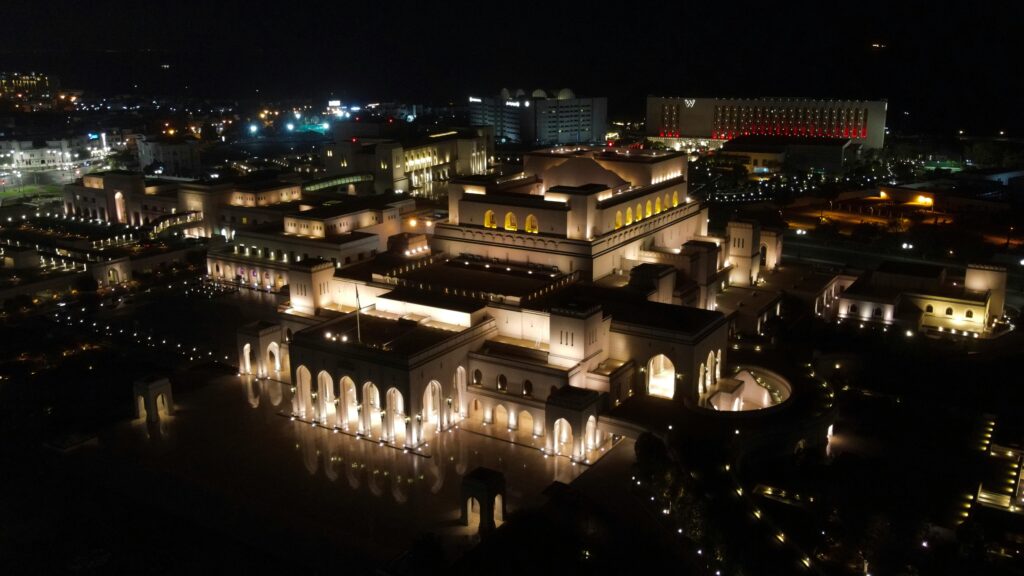 Aerial view of the illuminated Royal Opera House in Muscat at night.