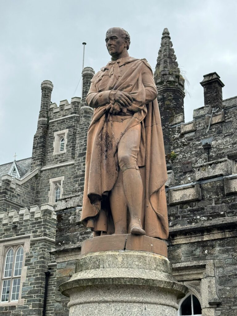 Stone statue of a historic figure in front of Lanhydrock House.
