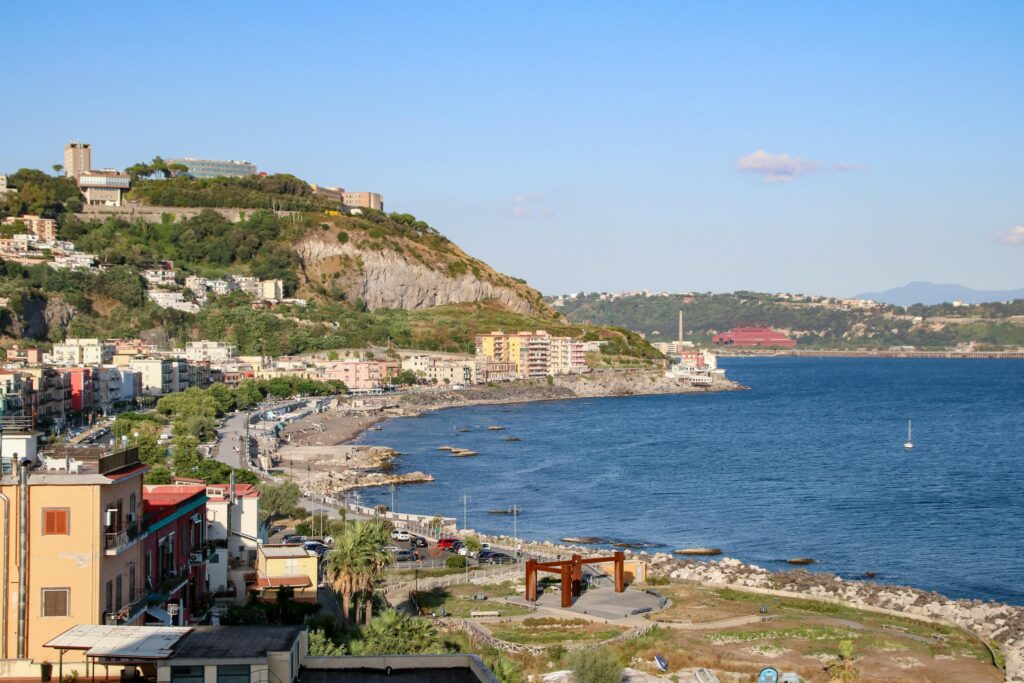 A scenic coastal view of Pozzuoli in Campania, Italy with cityscape and water.