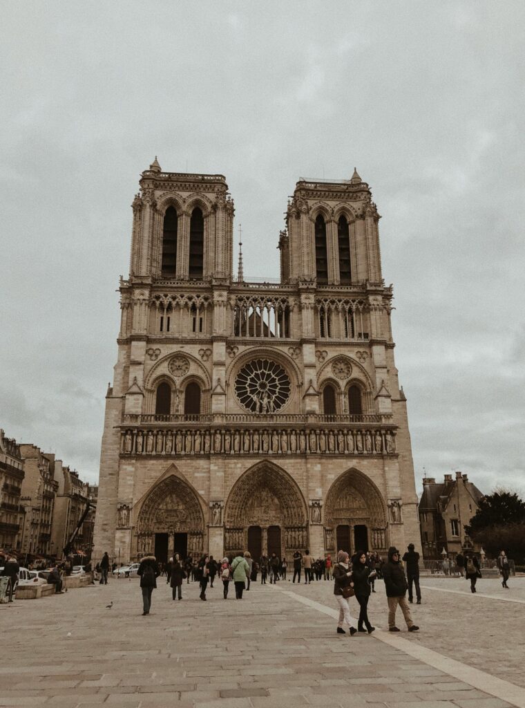 Front view of the iconic Notre-Dame Cathedral in Paris with people in the foreground.