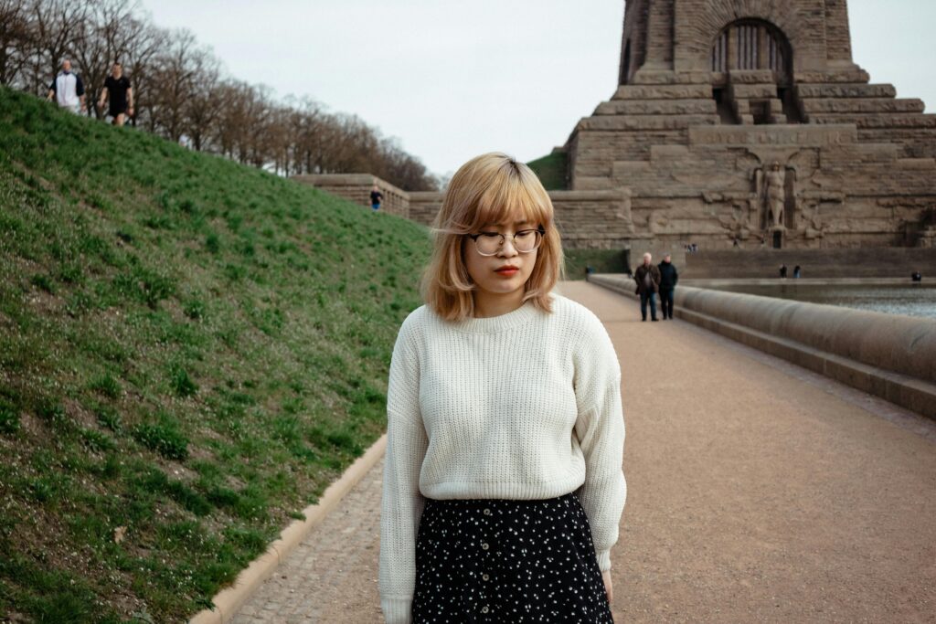 A woman in a knitted sweater stands at the iconic Völkerschlachtdenkmal in Leipzig, Germany.