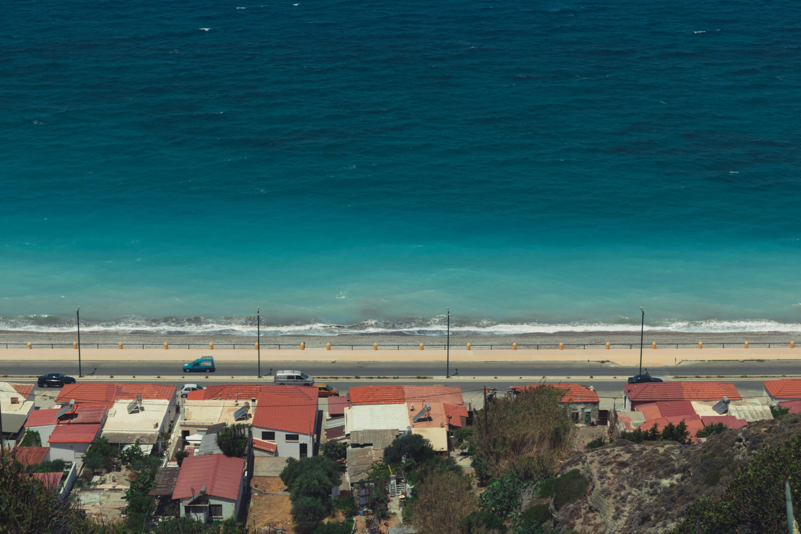A sweeping aerial view of Rodos houses near the turquoise ocean with clear skies.