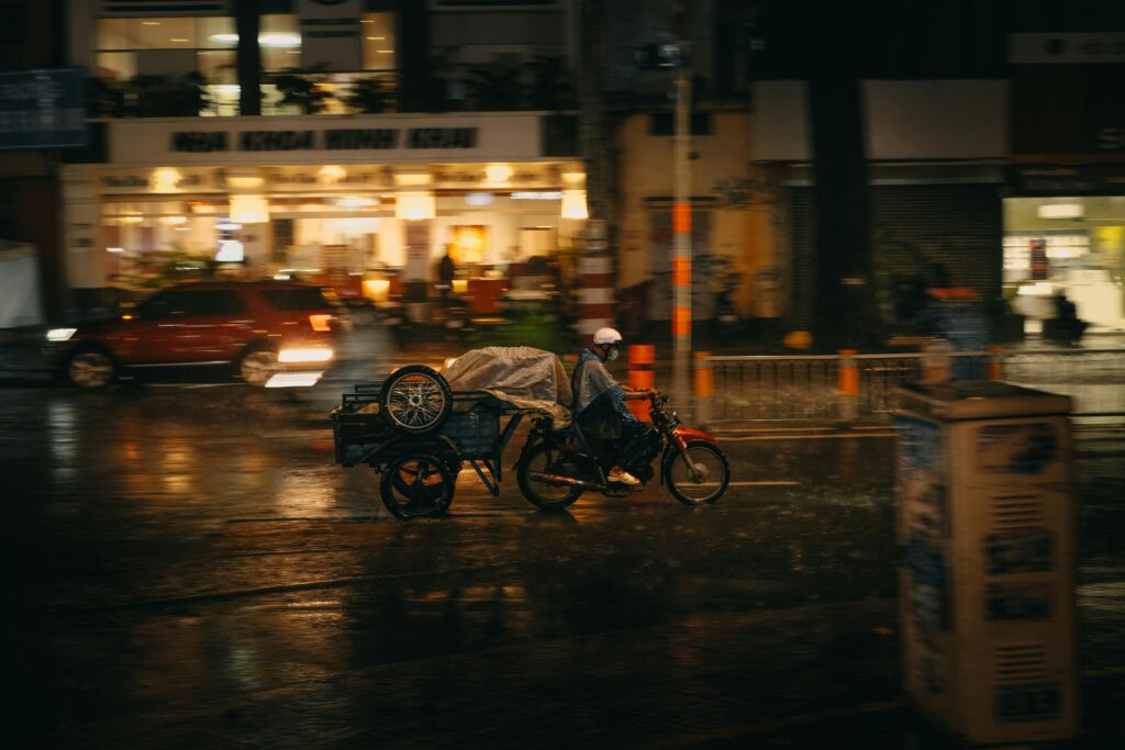 Person on a motorcycle rides through wet streets of Washington, DC at night, depicting urban life in the rain.