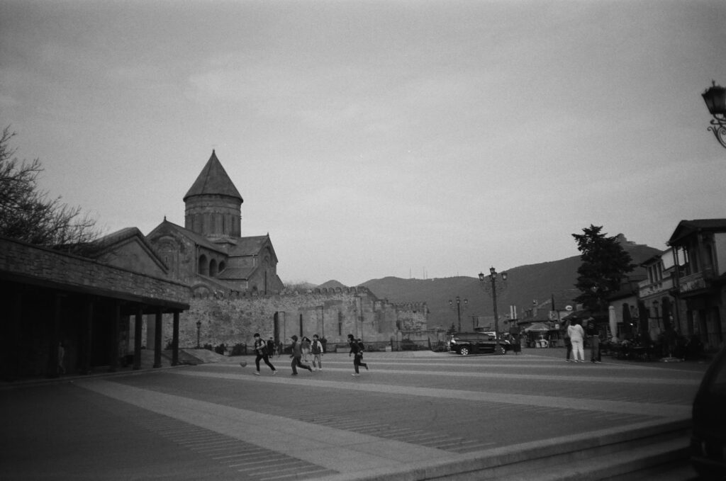 Black and white photo of children playing near a historic church in Georgia.