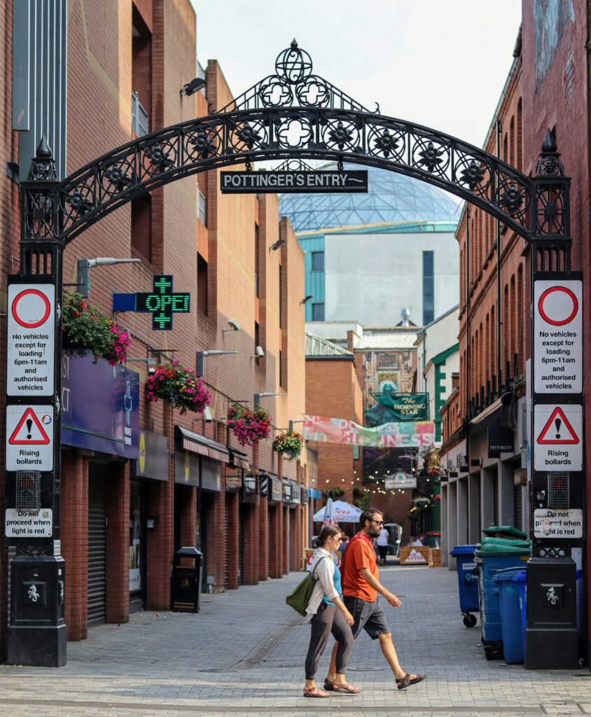 A couple walking under Pottinger's Entry arch in Belfast, city vibe captured.
