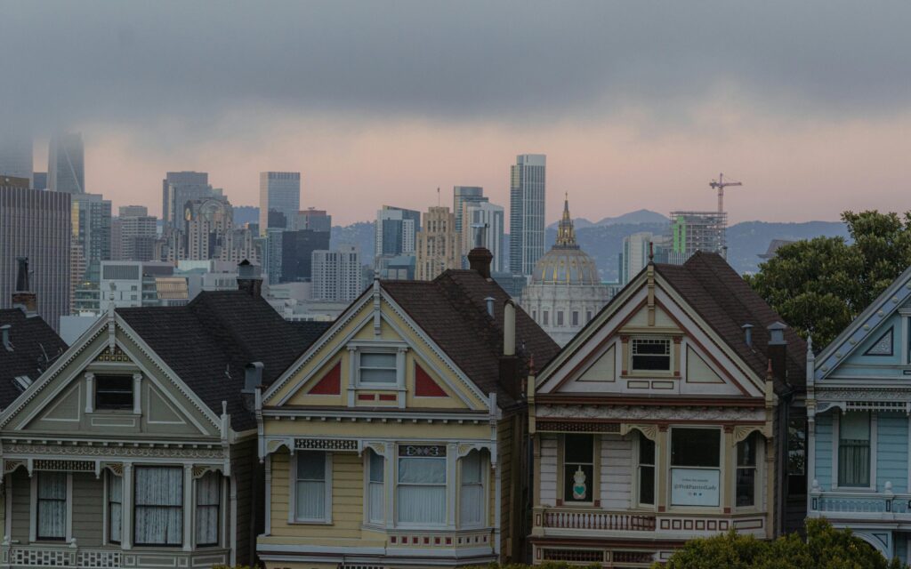 Iconic Painted Ladies with San Francisco skyline in the background at dusk.