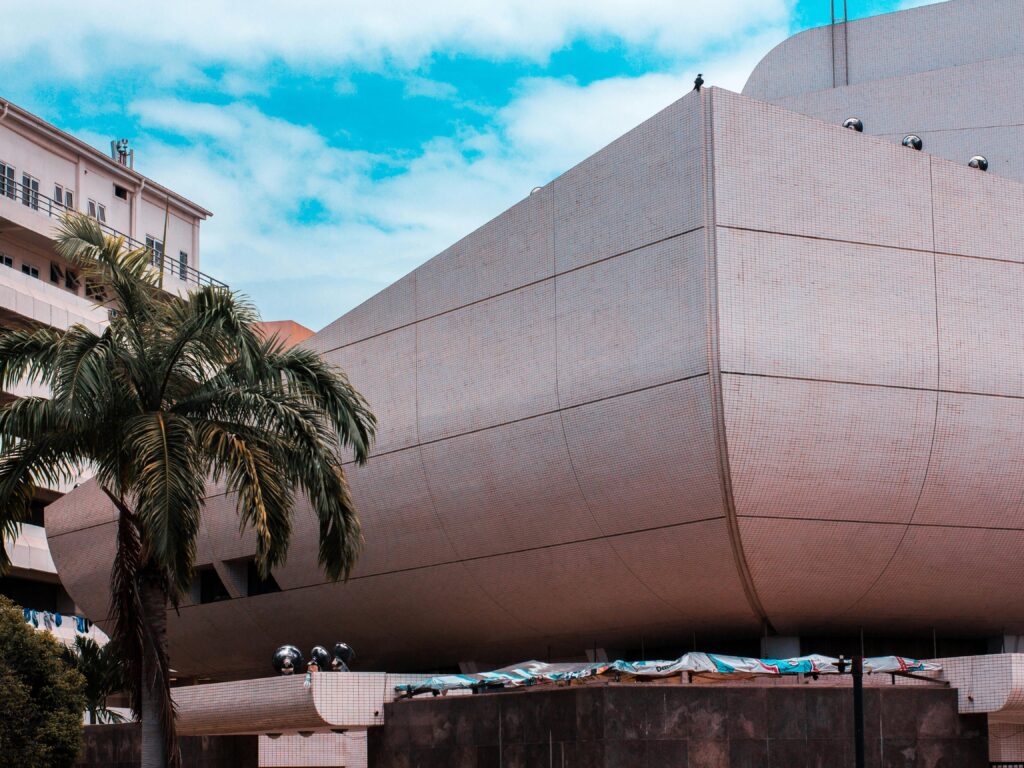 A striking modern building with a palm tree under a blue sky in Accra, Ghana.